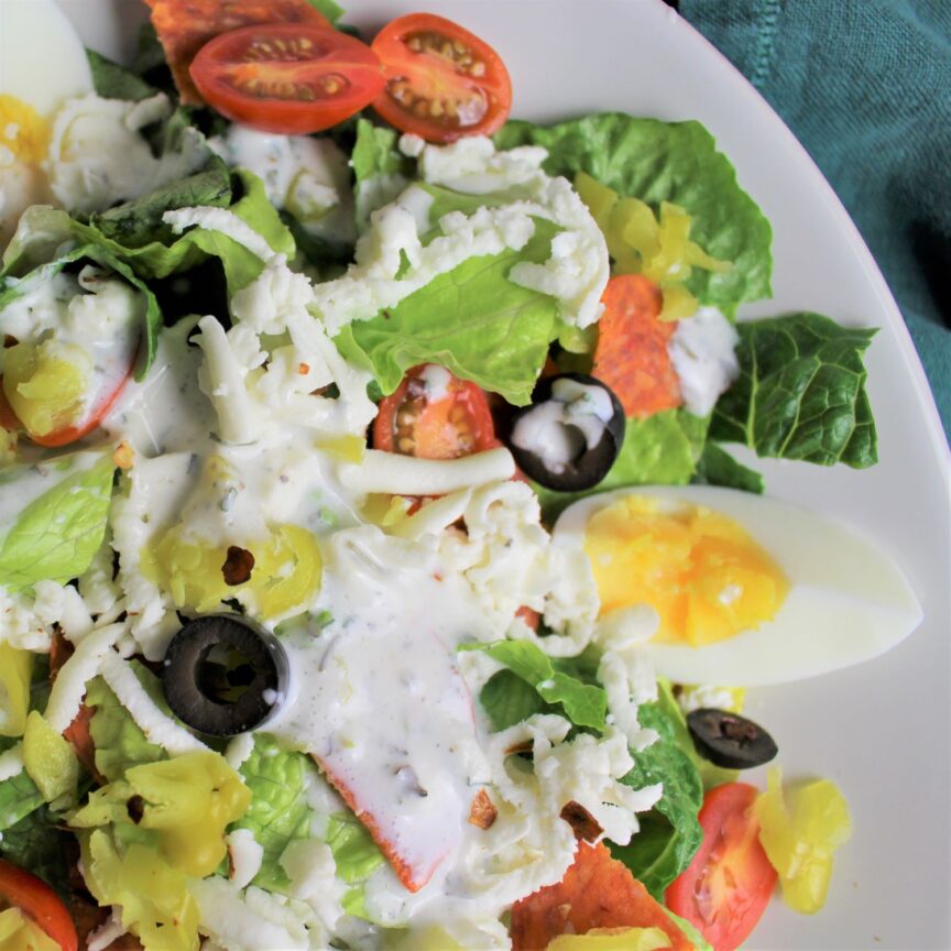 Romaine topped with halved cherry tomatoes, pepperoncinis, black olives, and mozzarella, drizzled with a healthy ranch dressing.