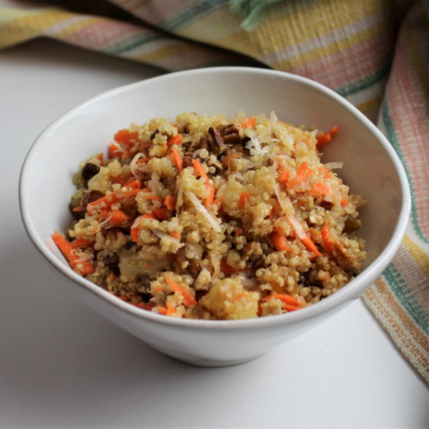 A bowl full of quinoa, golden raisins, pecans, coconut, and spices