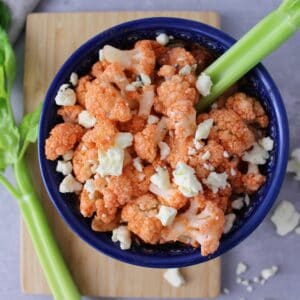 Steamed cauliflower in a bowl with Frank's hot sauce and blue cheese crumbles.