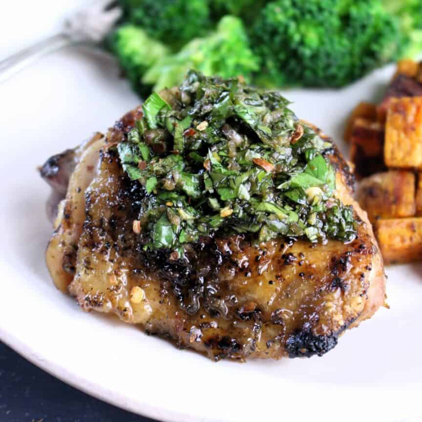 Perfectly grilled chicken thighs with Herby Chimichurri on top.