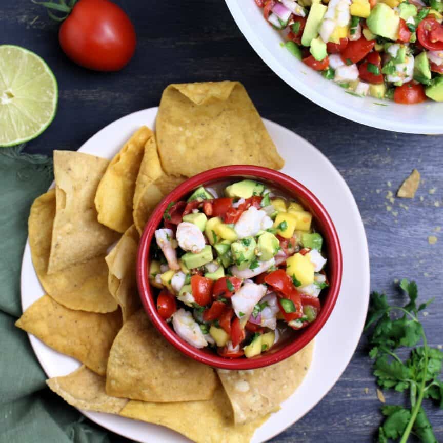 Bowl full of colorful Mango Shrimp Ceviche with Avocado, plated with tortilla chips.