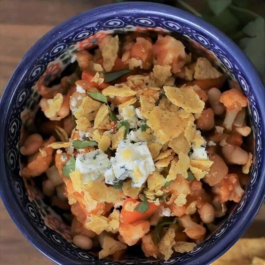 Bowl full of buffalo vegetarian chili with crushed tortilla chips and blue cheese crumbles.