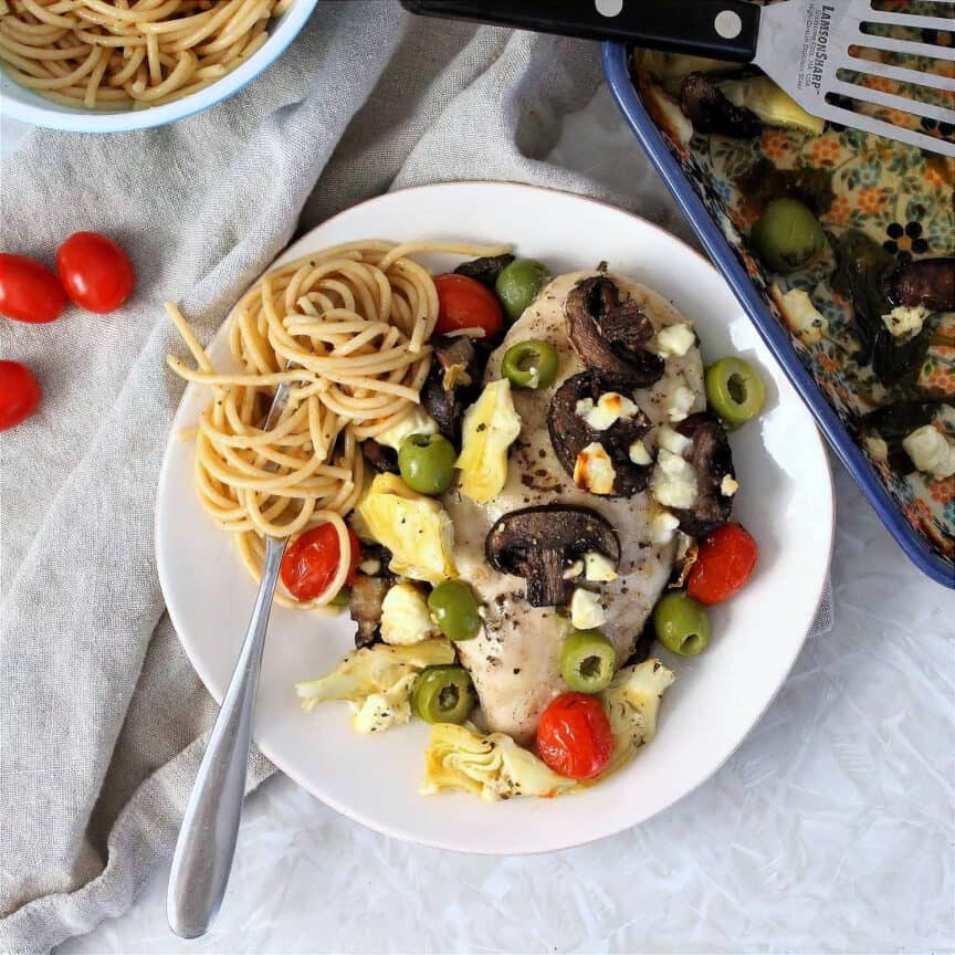 Plated chicken artichoke recipe with cherry tomatoes, mushrooms, olives, and feta.