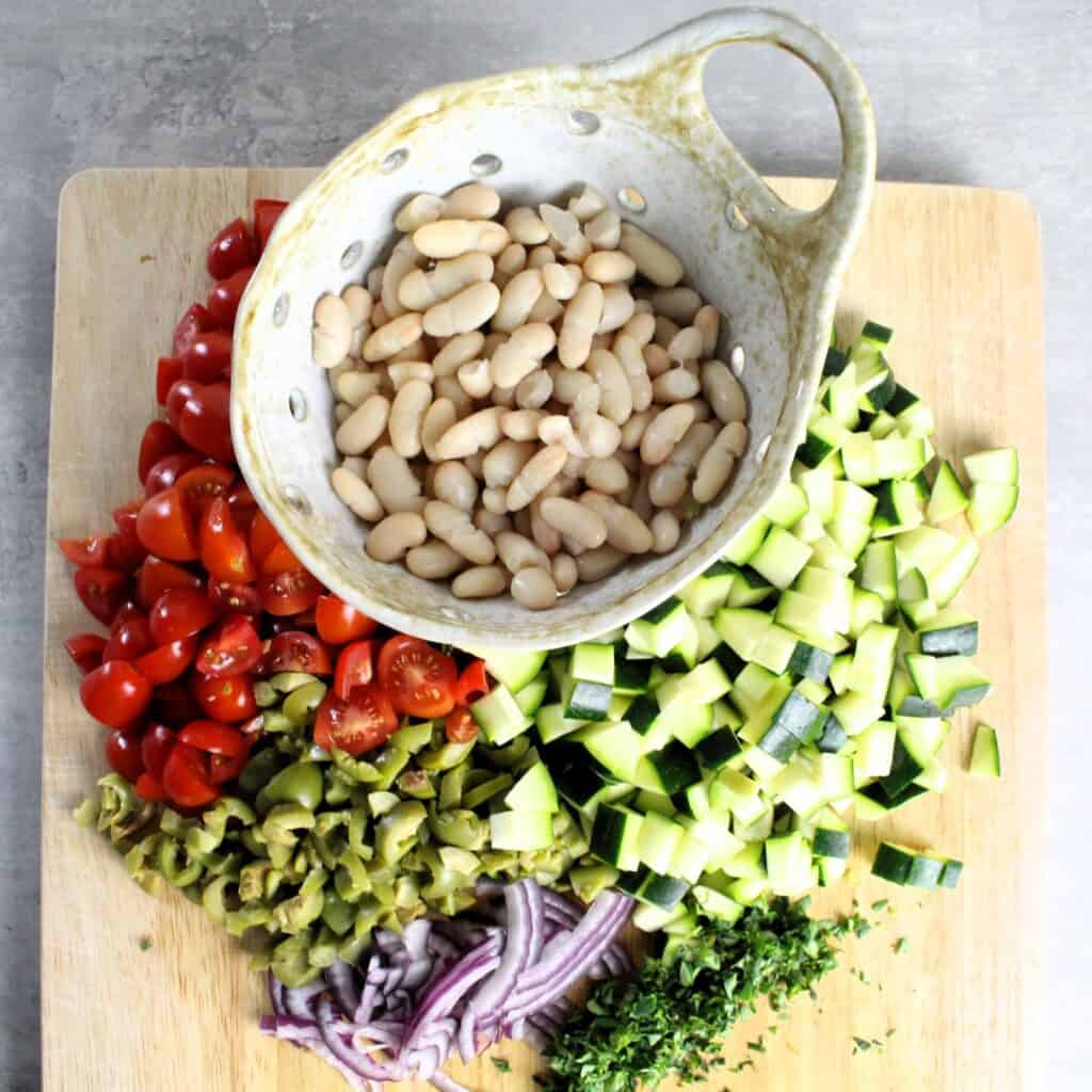 Beans, diced veggies, and chopped thyme on wooden cutting board.
